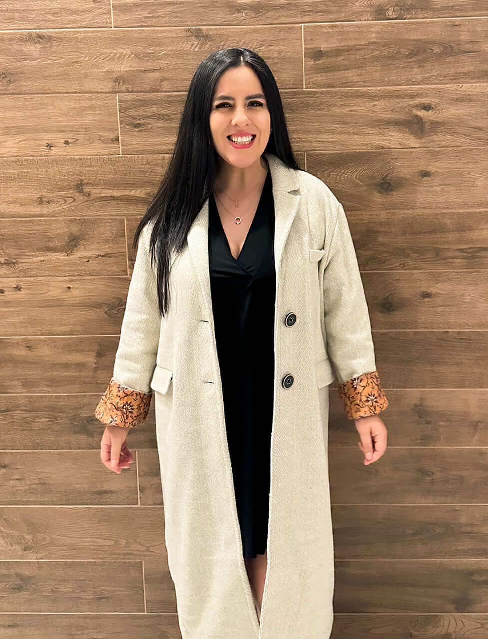 Naty parada frente a un fondo que simula madera
